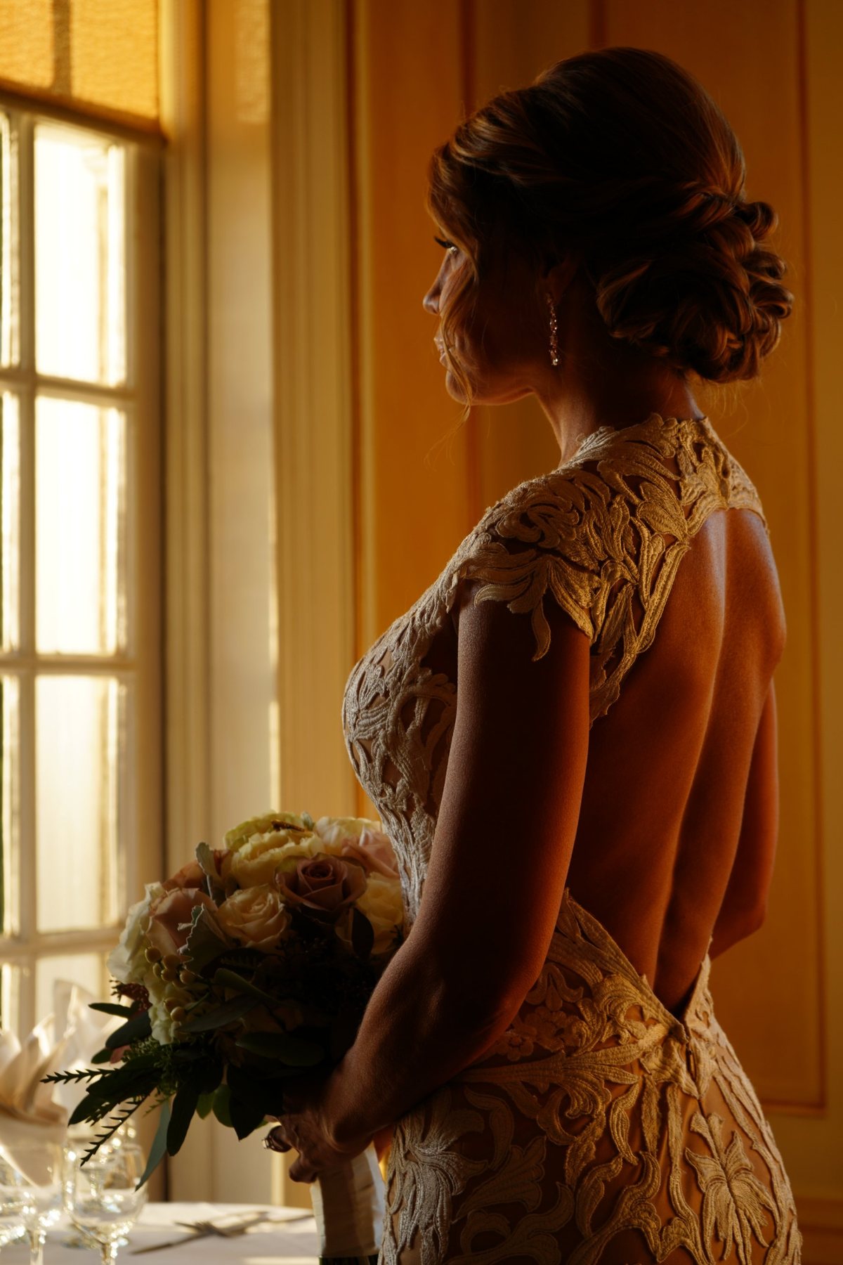 Bride in lace gown by a window